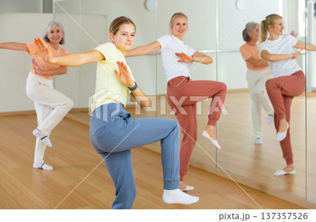 Teen girl with family doing aerobics exercises with group of people in dance center Teen girl with family doing aerobics exercises with group of people in dance center 137357526