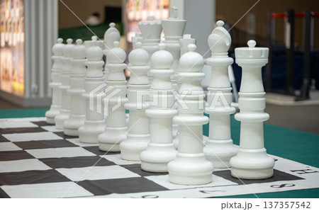 Giant white chess pieces standing on a large outdoor chessboard 137357542