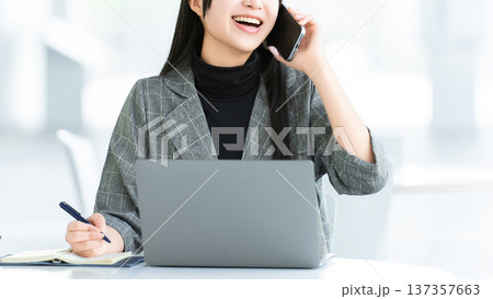スマートフォンで話す若い女性・ビジネスウーマン スマートフォンで話す若い女性・ビジネスウーマン 137357663