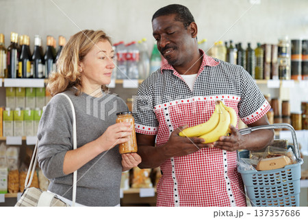 Married couple with various products in hands continuing shopping in grocery department of supermarket 137357686