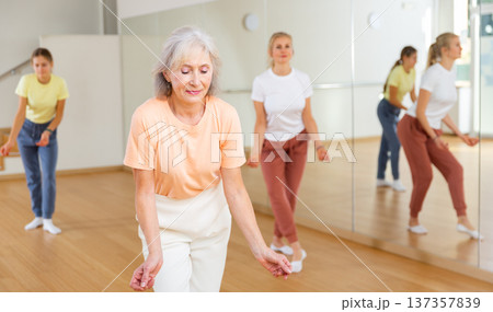 Elderly woman dancing jazz during group training Elderly woman dancing jazz during group training 137357839