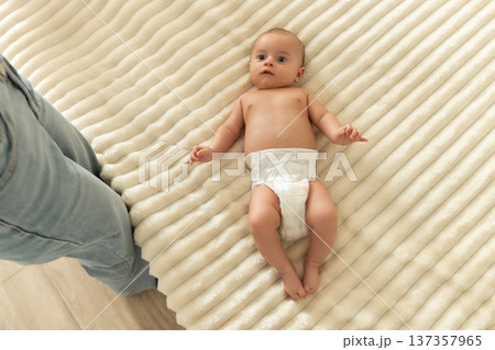 A baby lies on a soft blanket while being observed by a parent A baby lies on a soft blanket while being observed by a parent 137357965