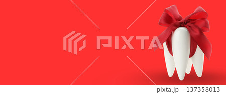 Tooth-shaped object with a red bow on a red surface Tooth-shaped object with a red bow on a red surface 137358013