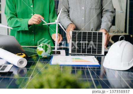 Two engineers collaborate on solar and wind energy, driving clean innovation and sustainability. A vision of teamwork 137358937