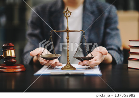Male lawyer in the office with brass scale on wooden table. justice and law concept in morning light 137358992