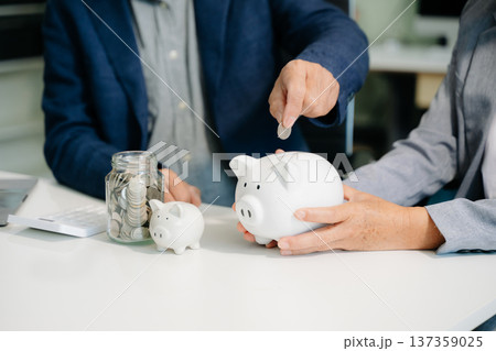 business team  holding coins putting in glass with using smartphone and calculator 137359025