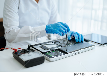 Electronics technician, electronic engineering electronic repair,electronics measuring and testing, repair and maintenance concepts.uses a voltage meter to check and upgrade 137359057