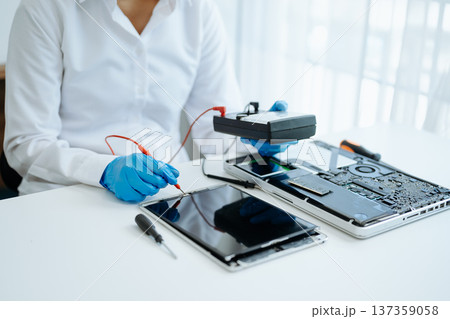 Electronics technician, electronic engineering electronic repair,electronics measuring and testing, repair and maintenance concepts.uses a voltage meter to check and upgrade 137359058