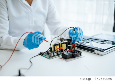 Electronics technician, electronic engineering electronic repair,electronics measuring and testing, repair and maintenance concepts.uses a voltage meter to check and upgrade Electronics technician, electronic engineering electronic repair,electronics measuring and testing, repair and maintenance concepts.uses a voltage meter to check and upgrade 137359060