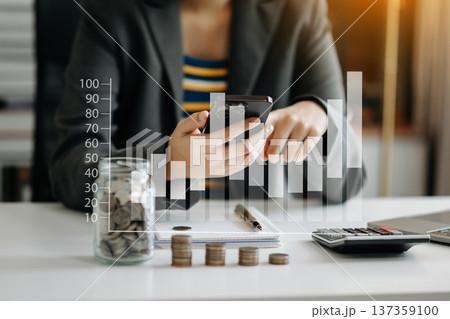 saving money with hand putting coins in jug glass and calculator to calculate budget concept finance and accounting and Gantt chart diagram. screen 137359100