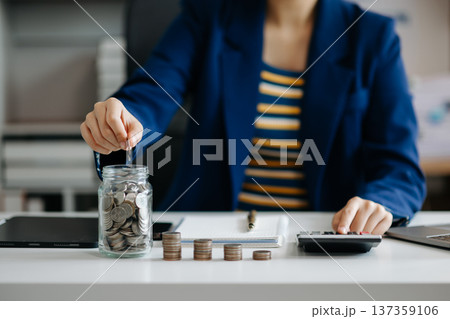 businesswoman holding coins putting in glass with using smartphone and calculator to calculate concept saving money for finance accounting in office businesswoman holding coins putting in glass with using smartphone and calculator to calculate concept saving money for finance accounting in office 137359106