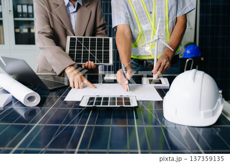 Two engineers collaborate on solar and wind energy, driving clean innovation and sustainability. A vision of teamwork Two engineers collaborate on solar and wind energy, driving clean innovation and sustainability. A vision of teamwork 137359135