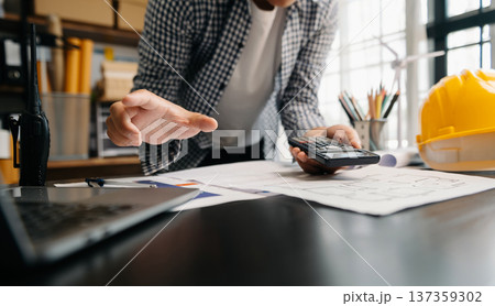 Engineer in helmet for workers security on office buildings and management on the construction drawing plan near laptop working in Engineering tools 137359302