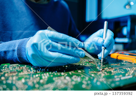 Close up of technician soldering and repairing circuit board in a modern laboratory, electronics repair, engineering, technology, maintenance and quality control concept. 137359392