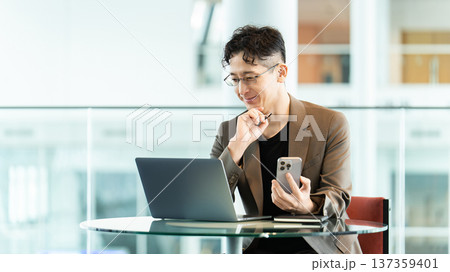 パソコンとスマートフォンを使う男性ビジネスマン パソコンとスマートフォンを使う男性ビジネスマン 137359401