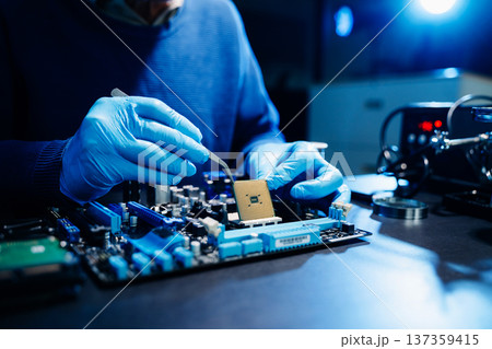 The technician is putting the CPU on the socket of the computer motherboard. electronic engineering electronic repair, electronics measuring and testing, repair The technician is putting the CPU on the socket of the computer motherboard. electronic engineering electronic repair, electronics measuring and testing, repair 137359415