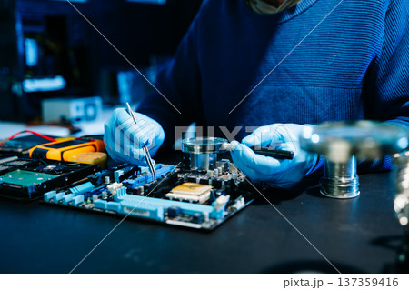 Closeup of expert soldering a green PCB board using precision tools. Ideal for electronics, circuit repair, engineering, tech Closeup of expert soldering a green PCB board using precision tools. Ideal for electronics, circuit repair, engineering, tech 137359416
