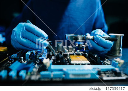Closeup of expert soldering a green PCB board using precision tools. Ideal for electronics, circuit repair, engineering, tech Closeup of expert soldering a green PCB board using precision tools. Ideal for electronics, circuit repair, engineering, tech 137359417