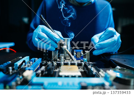 Closeup of expert soldering a green PCB board using precision tools. Ideal for electronics, circuit repair, engineering, tech 137359433