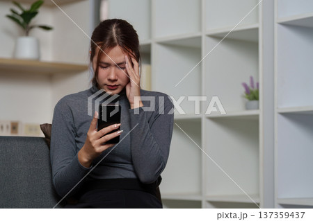 Digital Stress. A young woman feeling overwhelmed while using her smartphone. Digital Stress. A young woman feeling overwhelmed while using her smartphone. 137359437