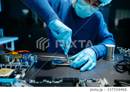 Closeup of expert soldering a green PCB board using precision tools. Ideal for electronics, circuit repair, engineering, tech 137359468
