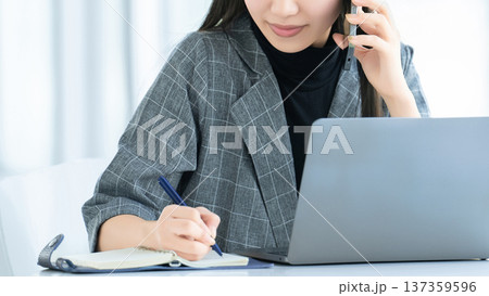 スマートフォンで話す若い女性・ビジネスウーマン 137359596