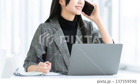 スマートフォンで話す若い女性・ビジネスウーマン スマートフォンで話す若い女性・ビジネスウーマン 137359598
