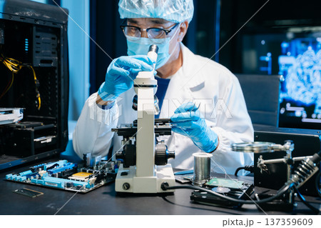 IT technician using microscope to inspect a motherboard in a modern lab. Electronics repair, precision work, troubleshooting, and system diagnostics 137359609