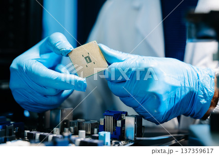 The technician is putting the CPU on the socket of the computer motherboard. electronic engineering electronic repair, electronics measuring and testing, repair The technician is putting the CPU on the socket of the computer motherboard. electronic engineering electronic repair, electronics measuring and testing, repair 137359617