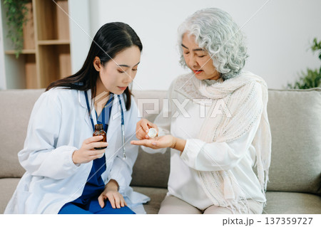 Female doctor helping senior woman take medication at home. Healthcare, elderly care, medical consultation, home healthcare, treatment guidance and wellness concept. Female doctor helping senior woman take medication at home. Healthcare, elderly care, medical consultation, home healthcare, treatment guidance and wellness concept. 137359727