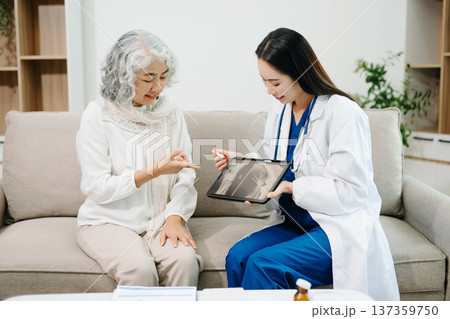 Doctor reviewing knee X-ray with elderly patient at home, highlighting arthritis, joint pain, orthopedic diagnosis, rehabilitation 137359750