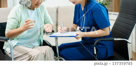 Asian nurse consulting elderly woman in wheelchair at home. Senior care, home healthcare, nursing support, communication and caregiver concept Asian nurse consulting elderly woman in wheelchair at home. Senior care, home healthcare, nursing support, communication and caregiver concept 137359785