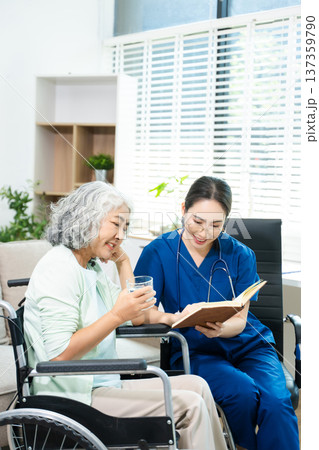 Asian nurse consulting elderly woman in wheelchair at home. Senior care, home healthcare, nursing support, communication and caregiver concept 137359790