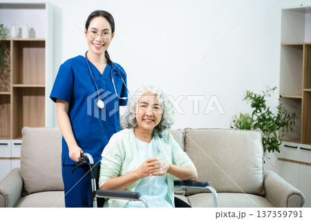 Asian nurse caring for smiling elderly woman in wheelchair at home. Senior care, home healthcare, nursing support, compassion, caregiver service concept 137359791