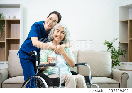Asian nurse caring for smiling elderly woman in wheelchair at home. Senior care, home healthcare, nursing support, compassion, caregiver service concept Asian nurse caring for smiling elderly woman in wheelchair at home. Senior care, home healthcare, nursing support, compassion, caregiver service concept 137359800