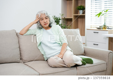 Depressed senior woman holding medication at home. Elderly mental health, loneliness, anxiety, sadness and healthcare concept in living room. Depressed senior woman holding medication at home. Elderly mental health, loneliness, anxiety, sadness and healthcare concept in living room. 137359818