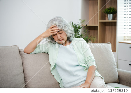 Depressed senior woman holding medication at home. Elderly mental health, loneliness, anxiety, sadness and healthcare concept in living room. 137359819