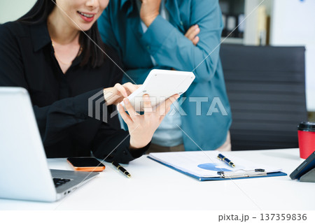 Asian businesswomen celebrating success in modern office. Teamwork, leadership, mentoring and collaboration concept with laptop and tablet. Asian businesswomen celebrating success in modern office. Teamwork, leadership, mentoring and collaboration concept with laptop and tablet. 137359836