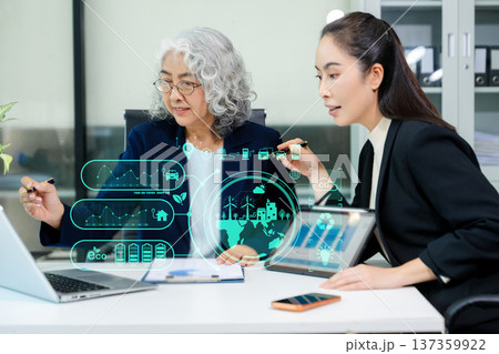Asian business women analyzing clean energy and renewable energy data using digital dashboard, reflecting ESG strategy, sustainability, innovation, and modern corporate environment. Asian business women analyzing clean energy and renewable energy data using digital dashboard, reflecting ESG strategy, sustainability, innovation, and modern corporate environment. 137359922