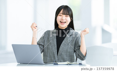 パソコンの前でガッツポーズをする若い女性・ビジネスウーマン 137359978