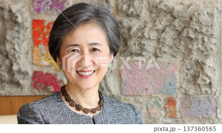 Smiling Woman With Gray Hair And Elegant Necklace Posed Against Textured Wall 137360565