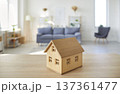 Closeup of little wooden toy house standing on table with empty living room in background 137361477