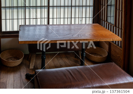 和風カフェの一枚板の木製テーブルと革張りのイス　障子越しの柔らかな光が差し込む古民家カフェの店内 137361504