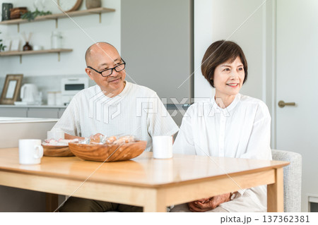 コーヒーを飲みながら家族と会話する笑顔のシニア夫婦 コーヒーを飲みながら家族と会話する笑顔のシニア夫婦 137362381
