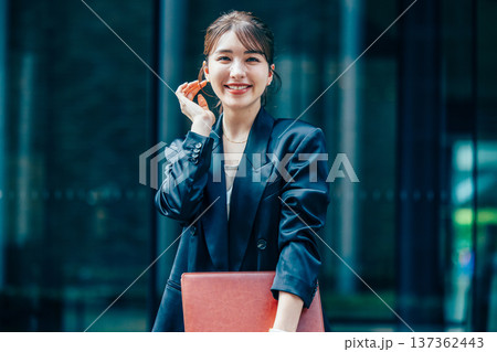 オフィスでスマホを使うスーツ姿の若いビジネスウーマン 137362443