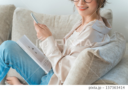 リビングのソファに座りスマホを見るアジア人女性 リビングのソファに座りスマホを見るアジア人女性 137363414