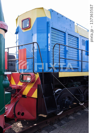 Colorful blue and yellow locomotive on railway tracks in an industrial setting during daytime 137363587
