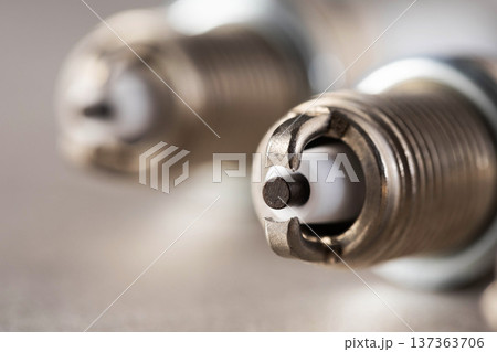 Detailed macro photograph of metallic automobile spark plugs, showing electrode tip, ground strap, and ceramic insulator, essential parts of combustion engine ignition Detailed macro photograph of metallic automobile spark plugs, showing electrode tip, ground strap, and ceramic insulator, essential parts of combustion engine ignition 137363706