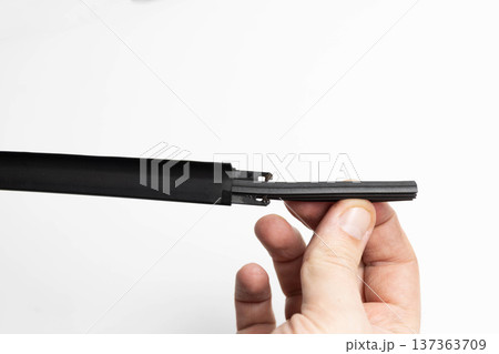 Hand holding car wiper blade component during rubber insert replacement process automotive maintenance procedure studio shot white background 137363709