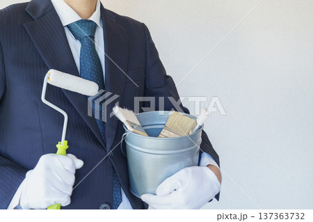 ペイントローラーと刷毛の入ったバケツを持つビジネスマン|リフォーム・塗装業者・DIY イメージ ペイントローラーと刷毛の入ったバケツを持つビジネスマン|リフォーム・塗装業者・DIY イメージ 137363732
